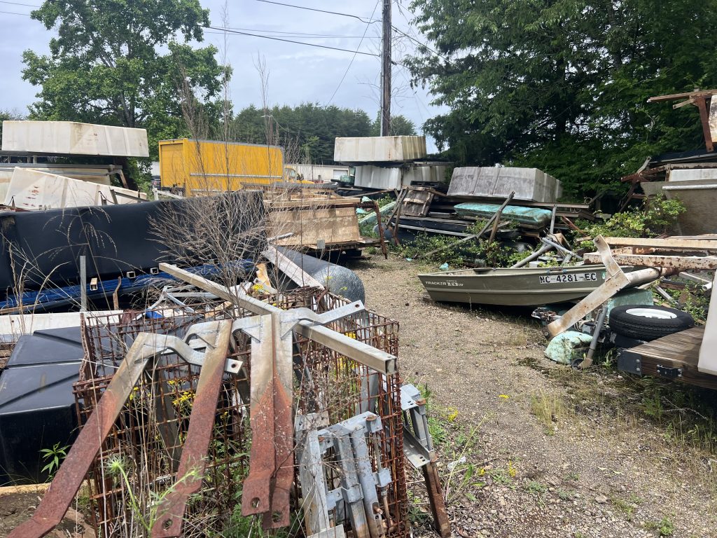 backyard filled with junk appliances, an old boat, and an old hot tub with Scrappy's Junk Removal truck